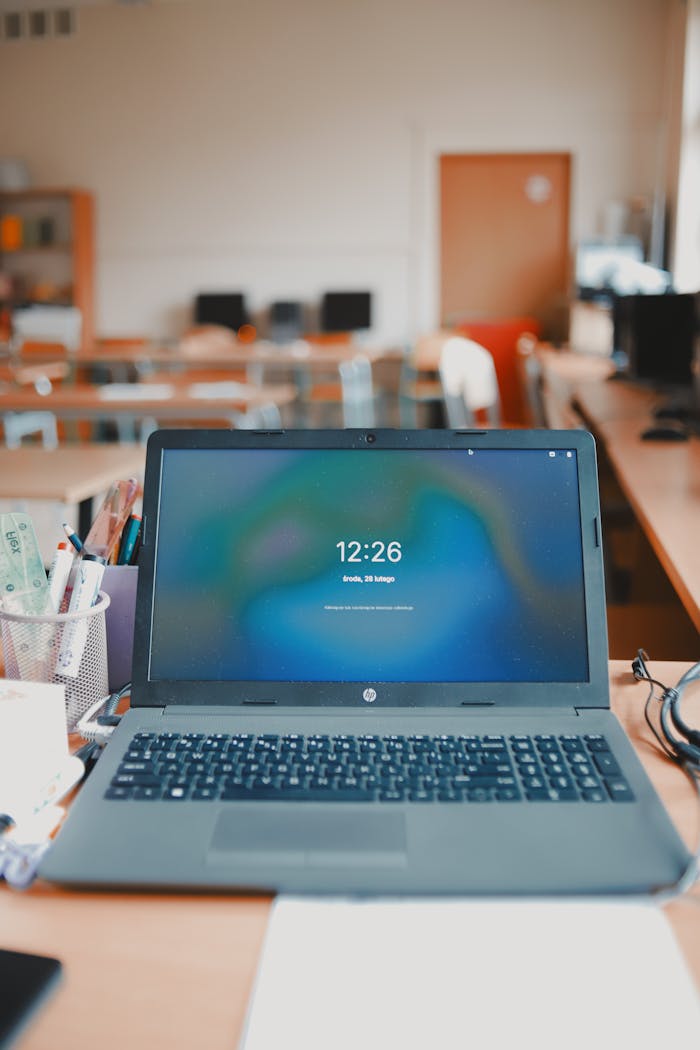 services-02 A laptop sits on a desk in a classroom setup, showcasing a modern educational environment.